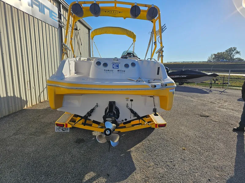 Slide: The Image of 2011 Tahoe 225 boat with yellow accents, parked outdoors on a trailer. - 2