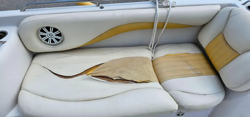 Slide: The Image of Damaged seat upholstery on 2011 Tahoe 225 boat, featuring torn white and yellow vinyl. - 5