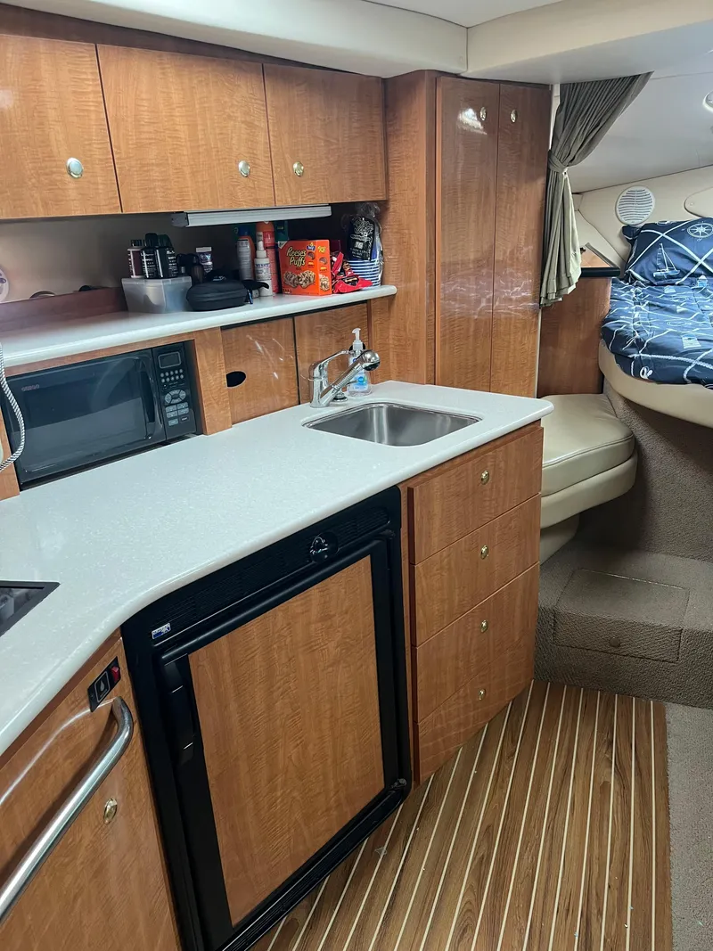 Slide: The Image of 2003 Maxum 3300 SCR yacht interior with kitchenette, sink, and cozy sleeping area. - 12