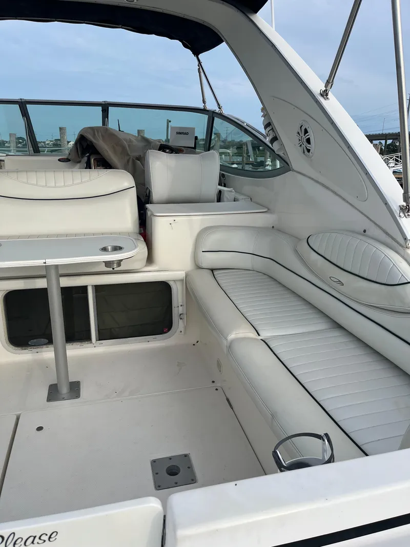 Slide: The Image of 2003 Maxum 3300 SCR boat interior with white seating and table, docked at marina. - 16