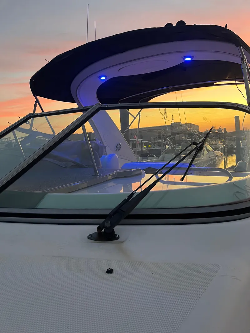 Slide: The Image of 2003 Maxum 3300 SCR boat at sunset with blue lights and marina background. - 21