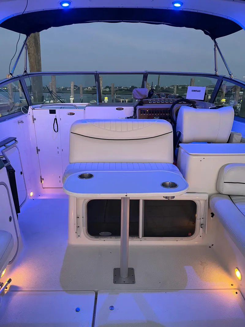 Slide: The Image of 2003 Maxum 3300 SCR boat interior with seating and table, illuminated by blue and yellow lights. - 22