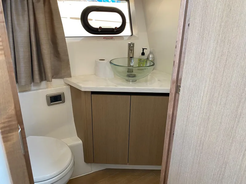 Slide: The Image of 2018 Sea Ray 400 Fly bathroom with modern sink and wooden cabinetry. - 32