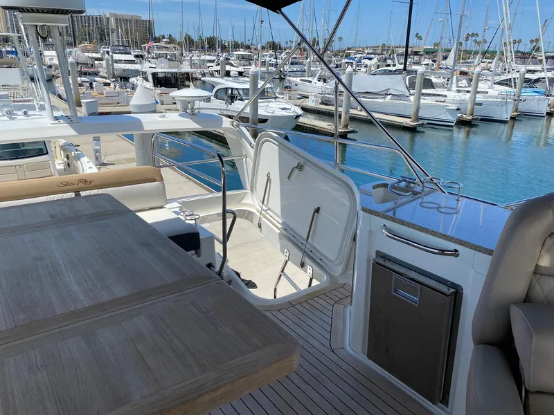 Slide: The Image of 2018 Sea Ray 400 Fly yacht interior with marina view, featuring seating and table. - 40