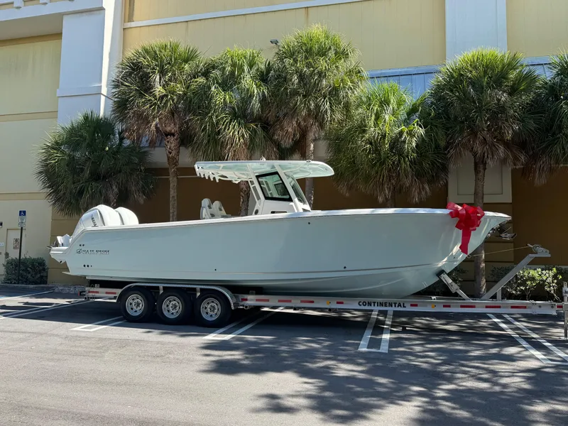 Slide: The Image of 2026 Sailfish 312 CC boat on trailer with red bow, parked near palm trees. - 1