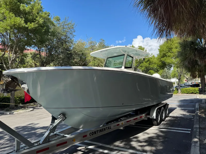 Slide: The Image of 2026 Sailfish 312 CC boat on trailer, parked under sunny skies with trees in background. - 2