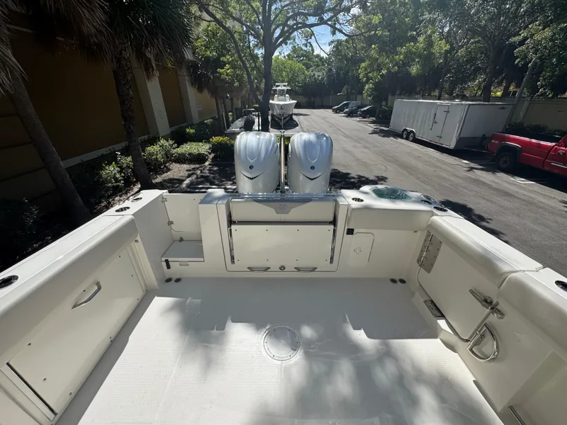 Slide: The Image of 2026 Sailfish 312 CC boat deck with dual engines, parked outdoors under trees. - 29