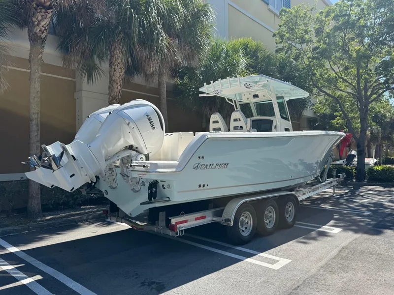 Slide: The Image of 2026 Sailfish 312 CC boat on trailer, parked under palm trees. - 3