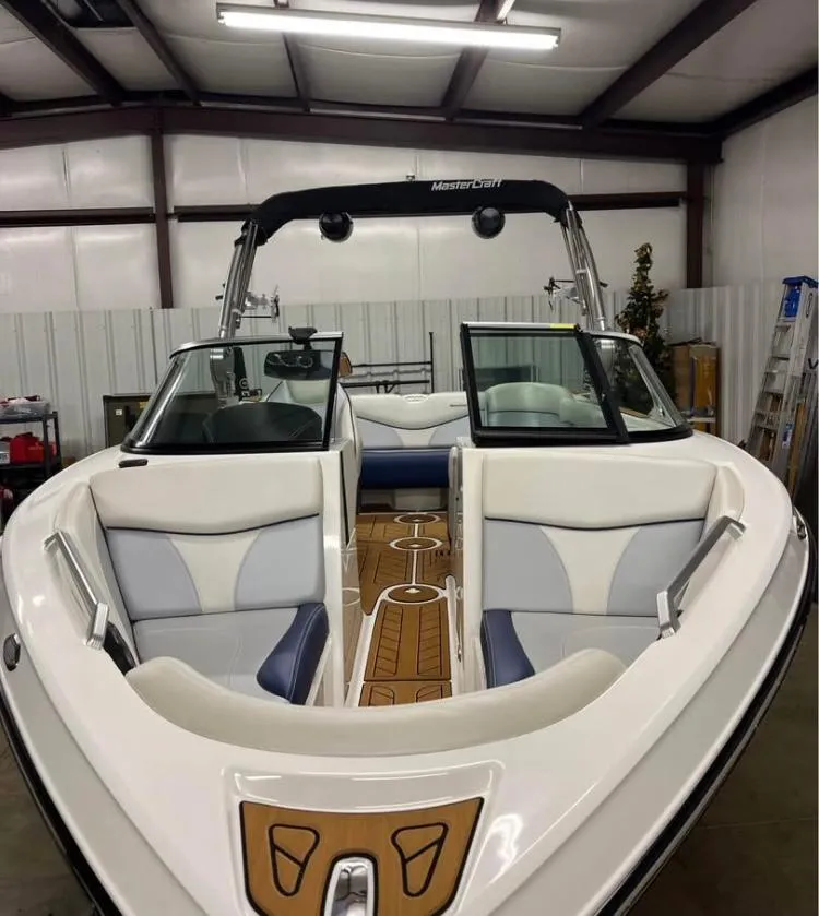 Slide: The Image of 2018 MasterCraft XT21 boat interior with white and blue seating, wooden flooring, and sleek design. - 4