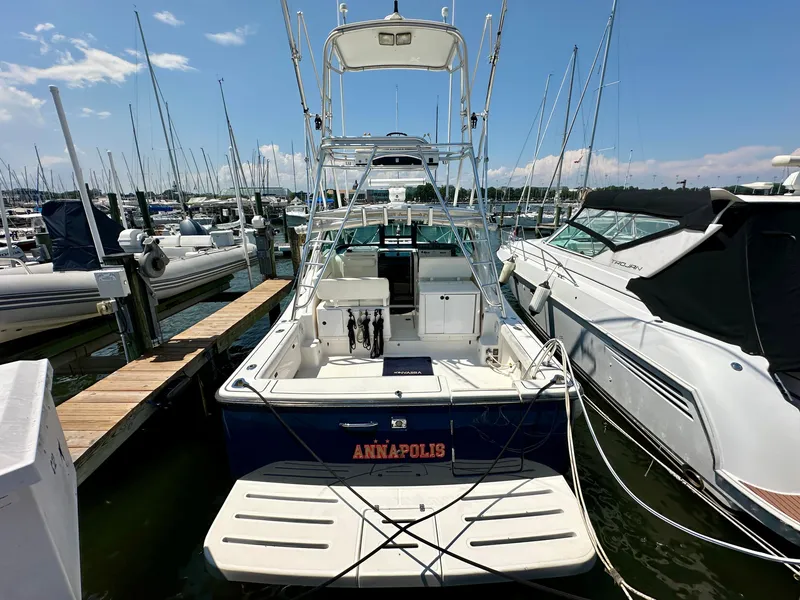 Slide: The Image of 2004 Tiara Yachts 3200 Open docked at marina, clear sky, surrounded by boats. - 3