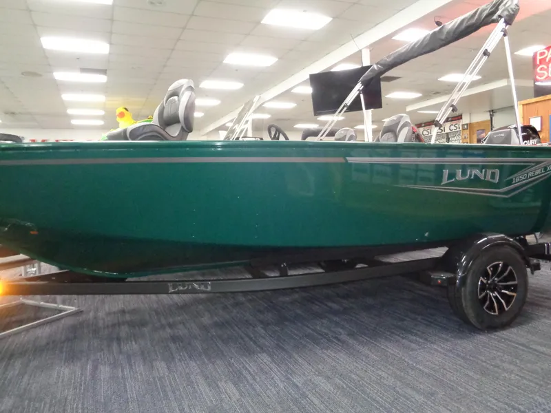 Slide: The Image of 2025 Lund 1650 Rebel XL SS boat in showroom, green exterior, on trailer. - 1