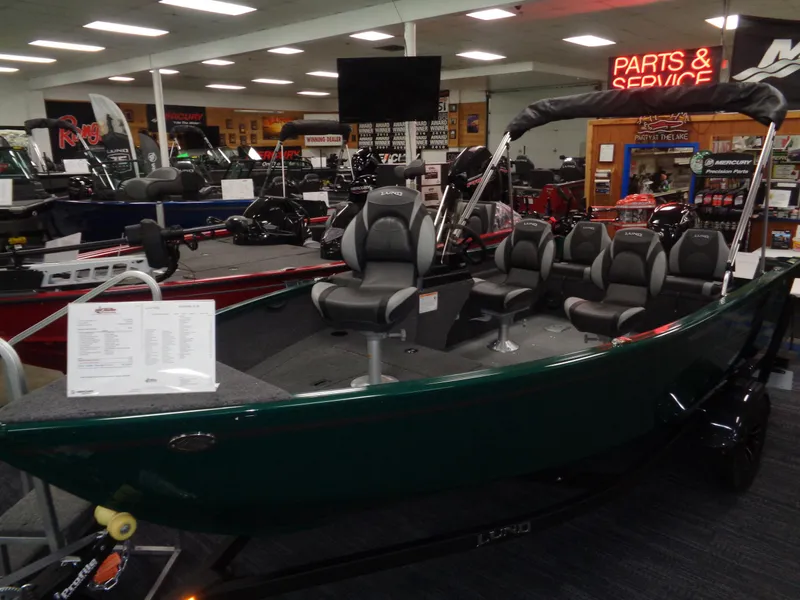 Slide: The Image of 2025 Lund 1650 Rebel XL SS boat displayed in showroom with seating and parts service area. - 18