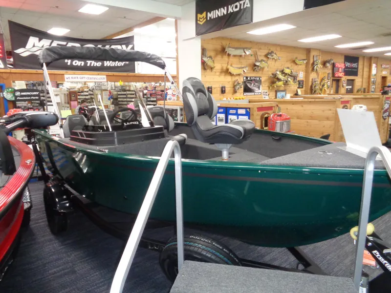 Slide: The Image of 2025 Lund 1650 Rebel XL SS boat displayed in a showroom with fishing gear. - 19