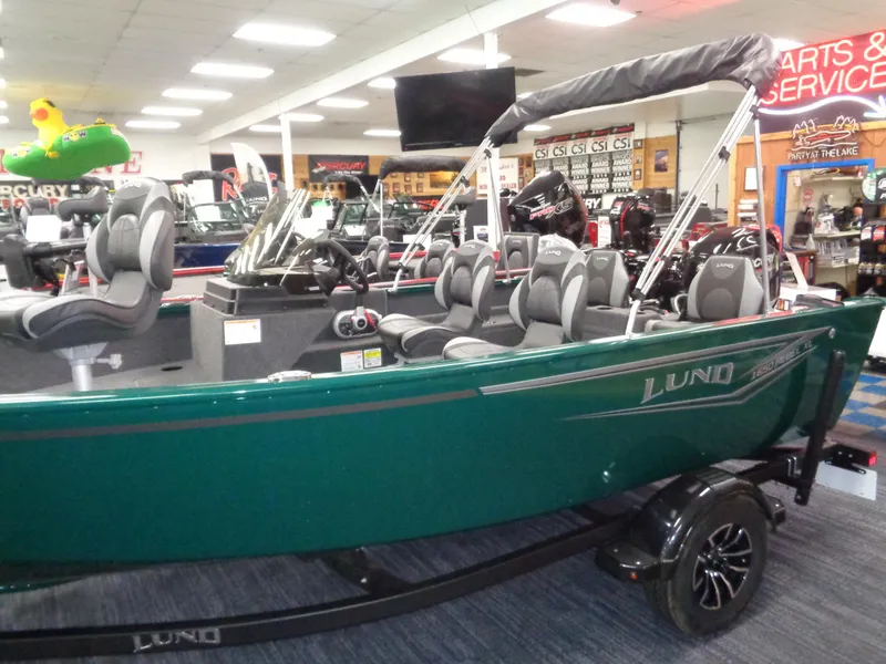 Slide: The Image of 2025 Lund 1650 Rebel XL SS boat displayed in showroom with seating and canopy. - 5