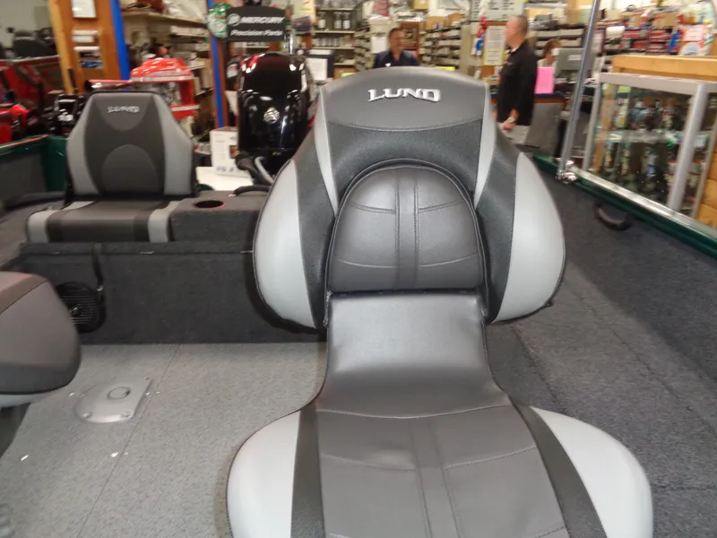 Slide: The Image of 2025 Lund 1650 Rebel XL SS boat interior with gray and black seating in showroom. - 8