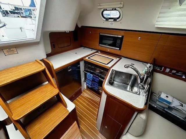 Slide: The Image of Compact kitchen in a 2017 Catalina 315 sailboat with wood finish and modern appliances. - 6
