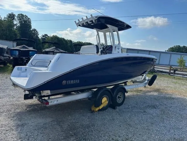 Slide: The Image of 2022 Yamaha Boats 255 FSH Sport E on trailer, blue and white, parked outdoors. - 2