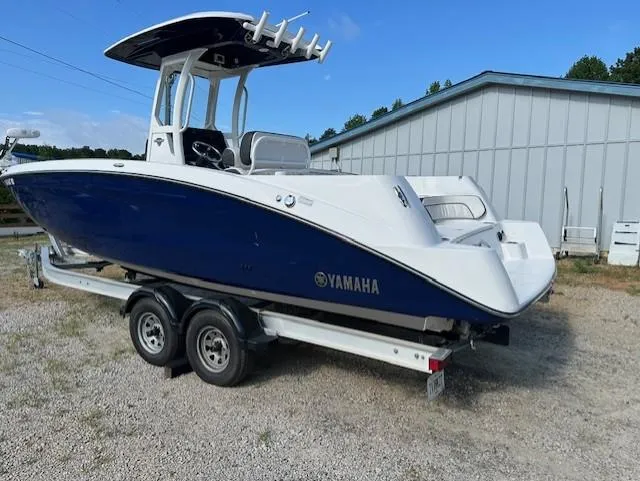 Slide: The Image of 2022 Yamaha Boats 255 FSH Sport E on trailer, blue and white design, parked outdoors. - 3