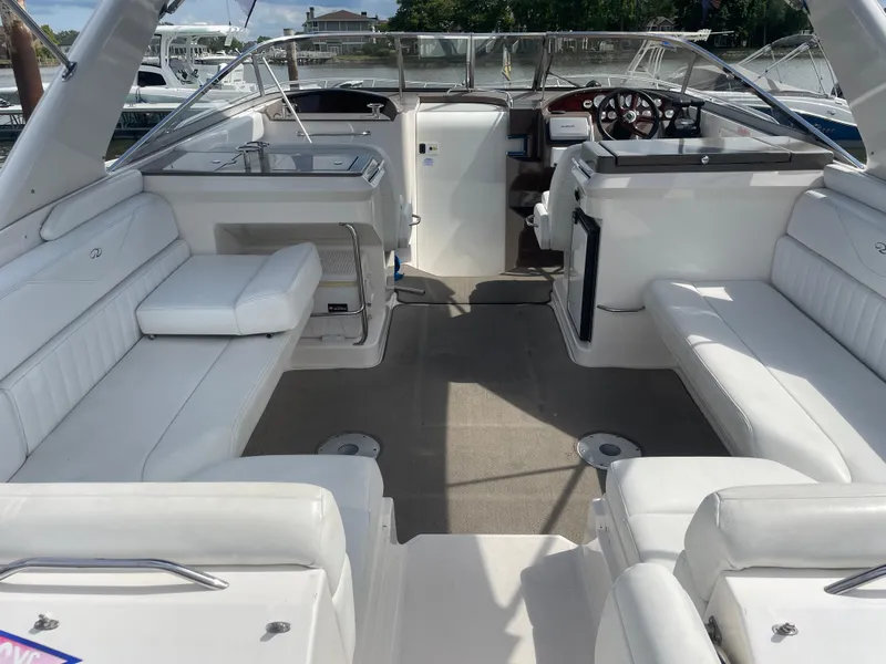 Slide: The Image of 2005 Regal 3350 Sport Cruiser interior with white seating and helm, docked at marina. - 16