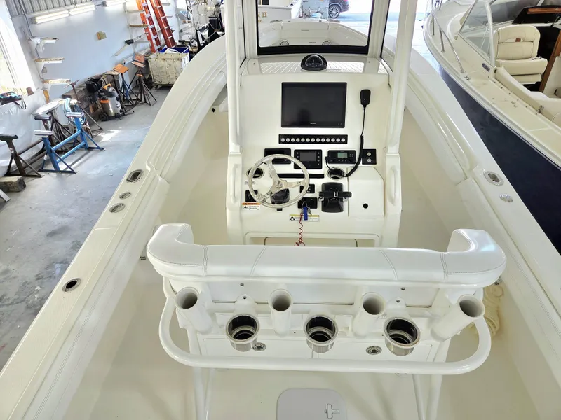 Slide: The Image of 2020 Regulator 25 boat interior with steering console and rod holders in a workshop setting. - 7