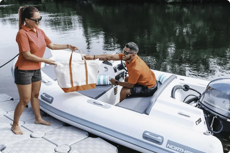 Slide: The Image of Couple loading bag onto 2022 Northstar Axis 3.1 boat at dock. - 3