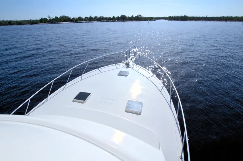 Slide: The Image of 1990 Post 44 Sport Fisherman boat on calm water, sun reflecting on deck. - 16