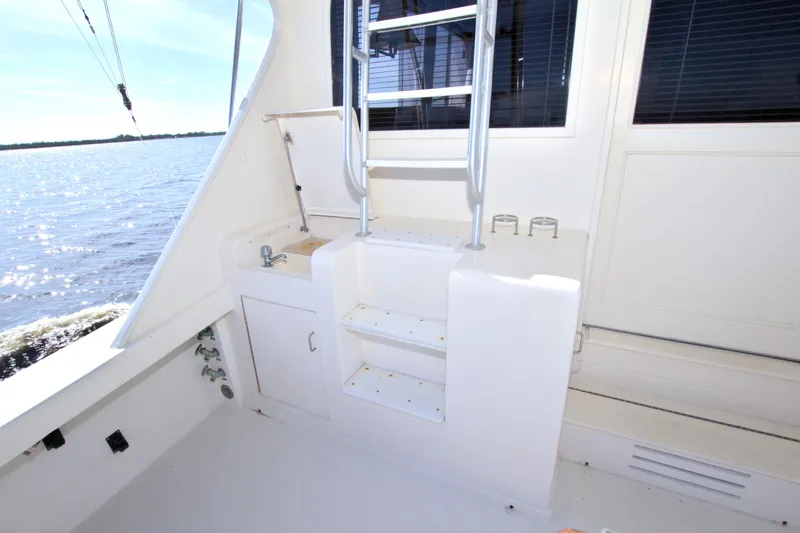 Slide: The Image of 1990 Post 44 Sport Fisherman boat deck with ladder and sink, overlooking water. - 22
