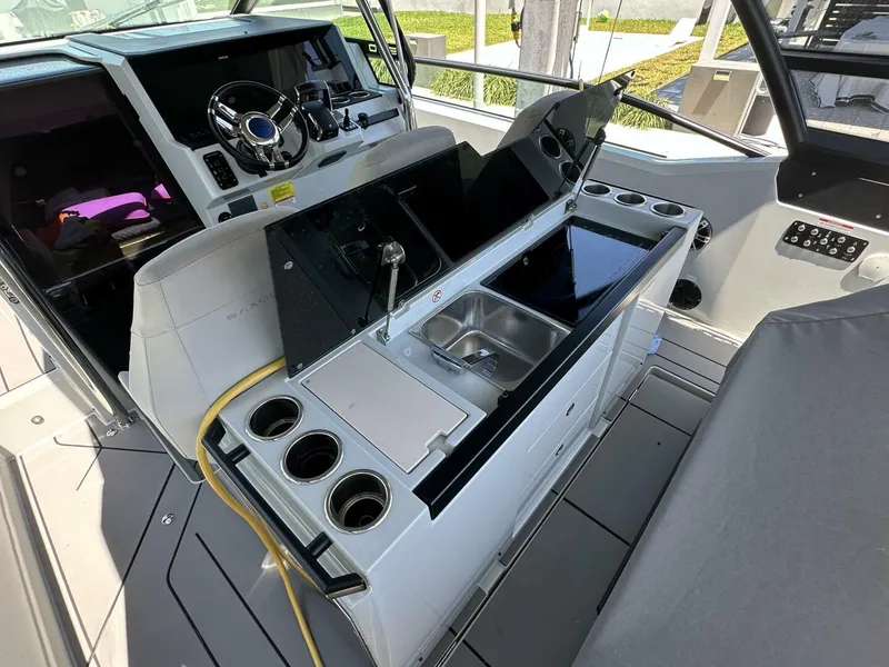 Slide: The Image of 2022 Saxdor 320 GTO boat interior with helm, sink, and cup holders. - 7