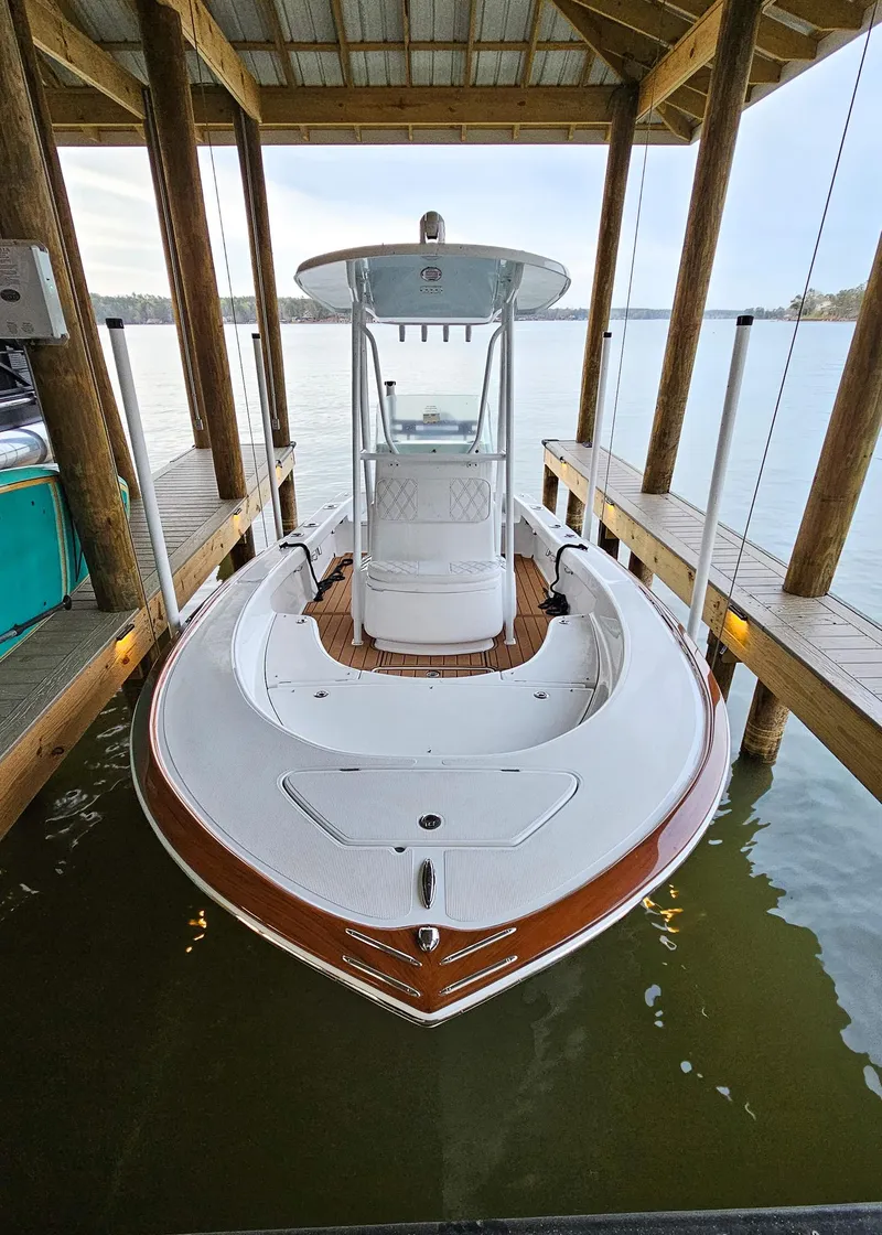 Slide: The Image of 2025 Chaos 21 Tarpon Bay boat docked under a wooden shelter. - 9