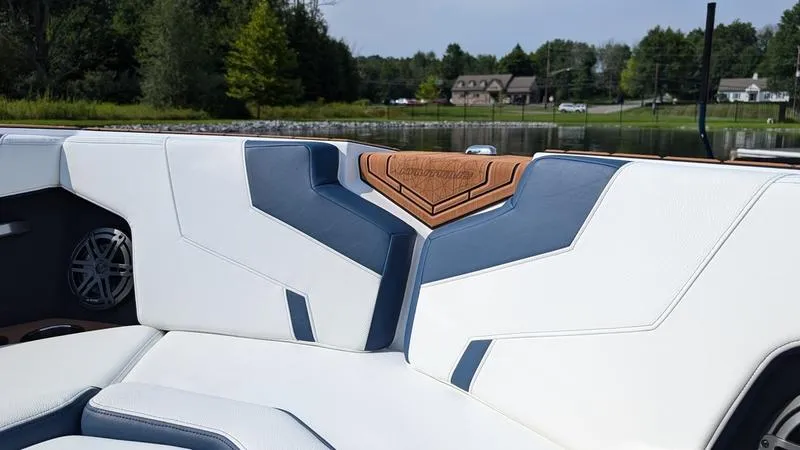 Slide: The Image of 2025 Nautique Super Air Nautique GS22 interior with white and blue seating, lake view background. - 14
