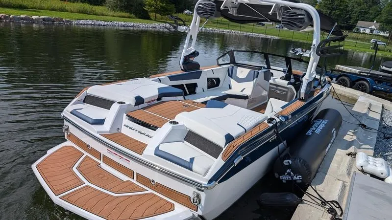 Slide: The Image of 2025 Nautique Super Air Nautique GS22 boat docked on a calm lake. - 7