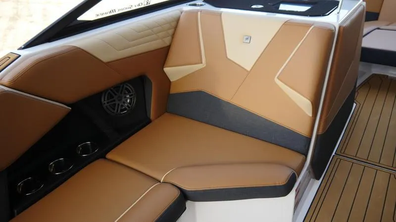 Slide: The Image of 2025 Nautique Super Air Nautique S23 interior with tan leather seating and cup holders. - 10