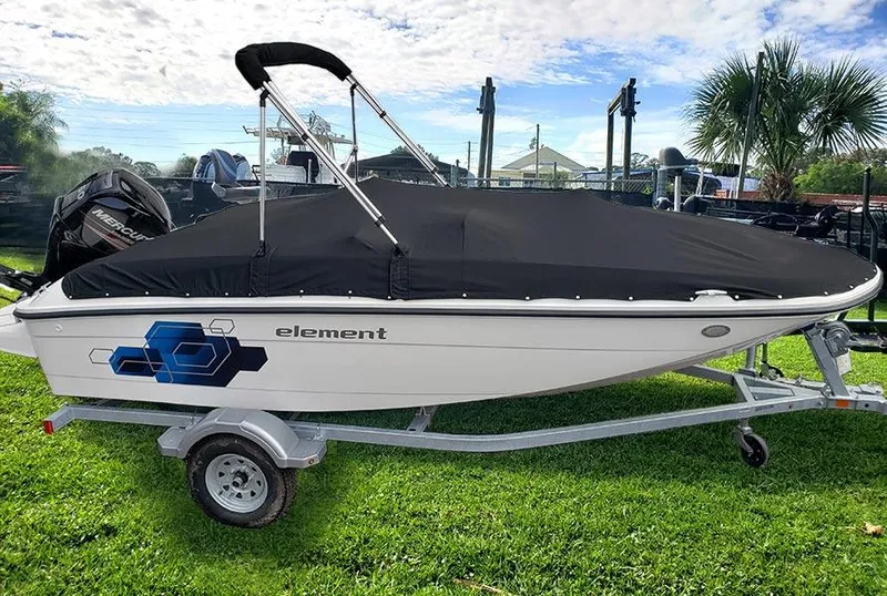 Slide: The Image of 2021 Bayliner Element E16 boat on trailer with cover, parked on grass. - 2