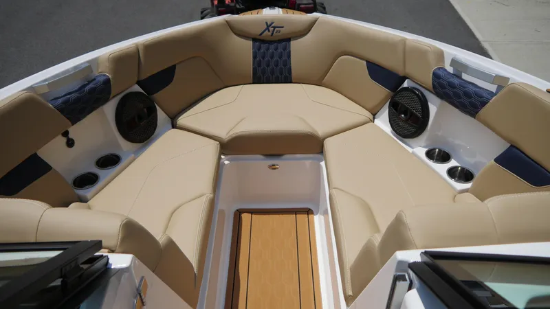 Slide: The Image of 2025 MasterCraft XT23 boat interior with beige and blue seating, cup holders, and speakers. - 11