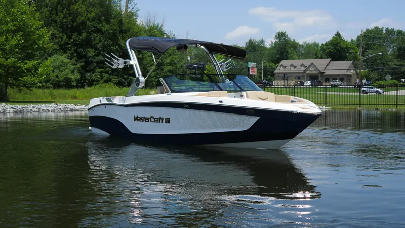 Slide: The Image of 2025 MasterCraft XT23 boat on a calm lake, surrounded by lush greenery. - 3