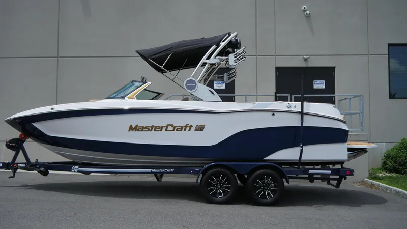 Slide: The Image of 2025 MasterCraft XT23 boat on trailer, side view, parked outdoors. - 5