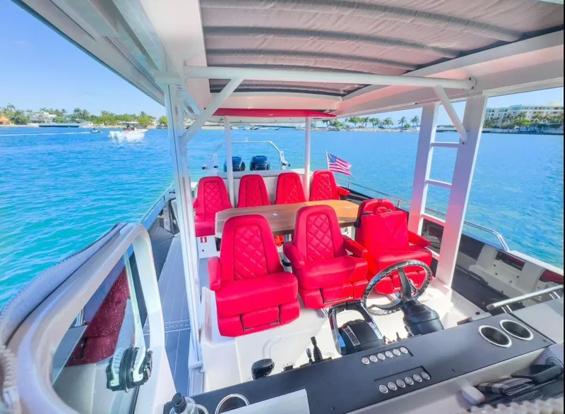 Slide: The Image of 2018 Axopar 37 Sun-Top boat with red seating, steering wheel, and ocean view. - 10