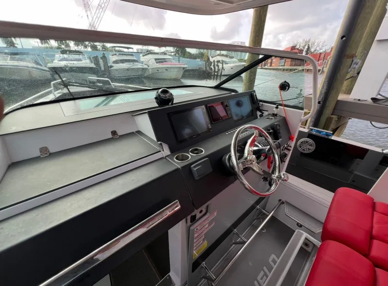 Slide: The Image of 2018 Axopar 37 Sun-Top boat helm with red seating and modern controls. - 11