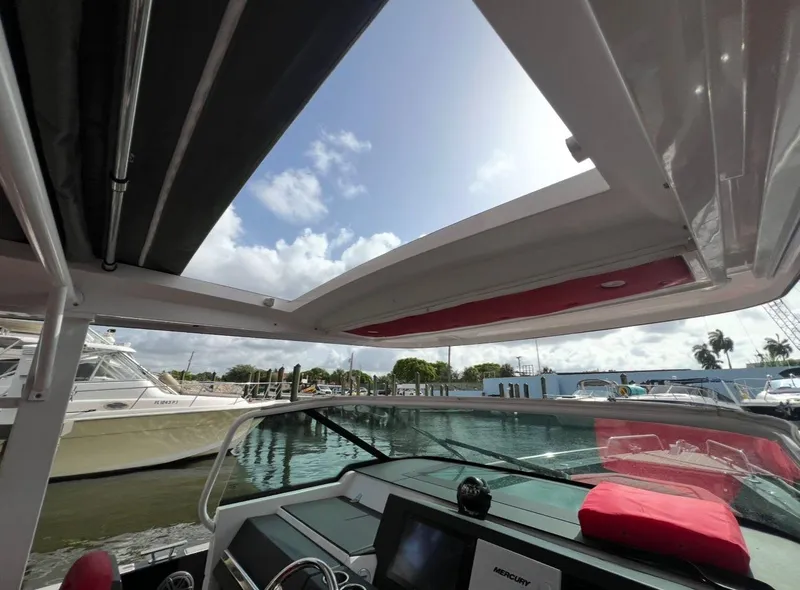 Slide: The Image of 2018 Axopar 37 Sun-Top boat interior with open roof, docked at marina. - 12