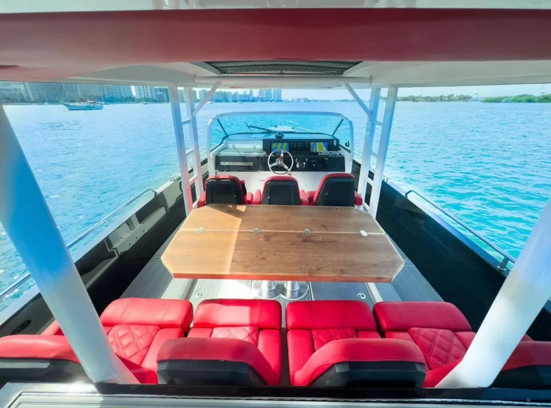 Slide: The Image of 2018 Axopar 37 Sun-Top boat with red seating and wooden table on open water. - 8