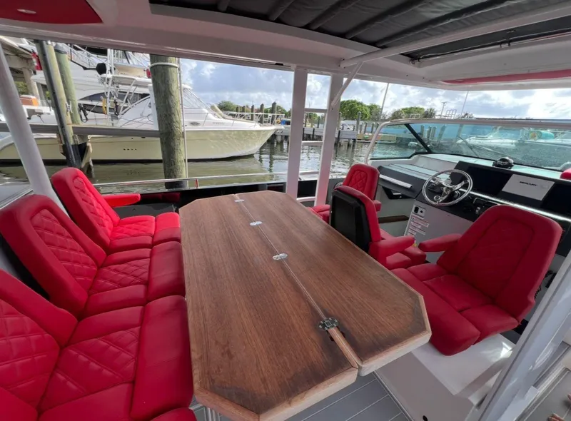 Slide: The Image of 2018 Axopar 37 Sun-Top boat interior with red seating and wooden table. - 9