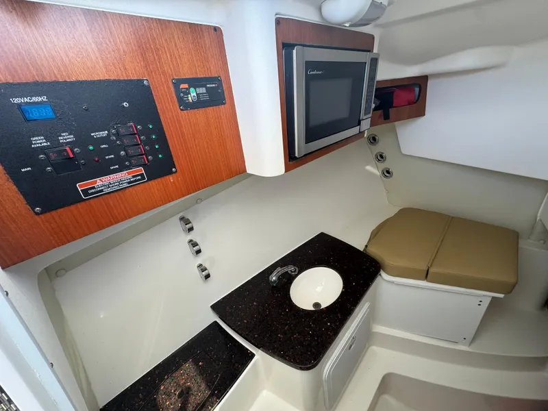 Slide: The Image of Interior of a 2014 Edgewater 280 CX boat featuring a control panel, microwave, and compact sink area. - 12