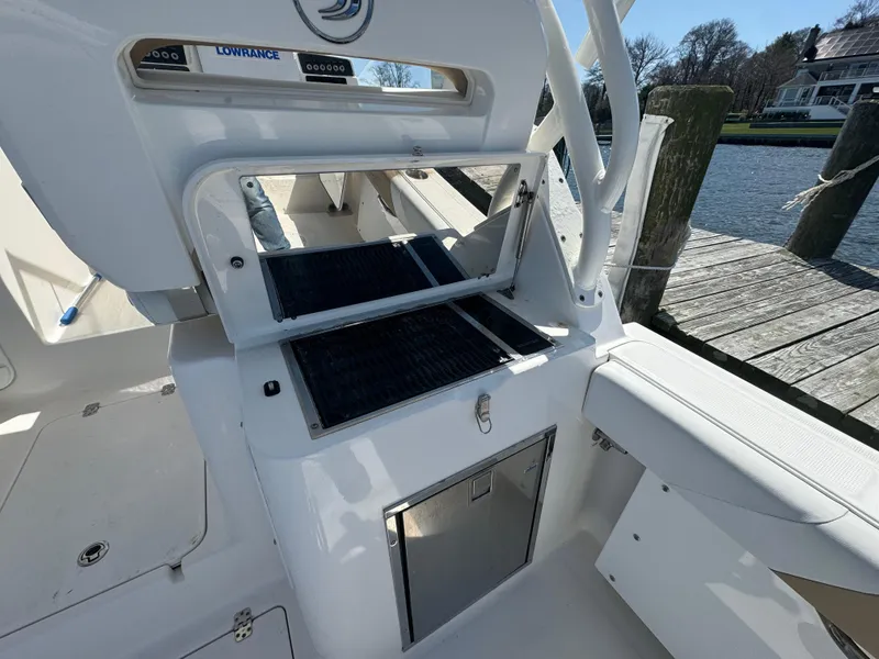 Slide: The Image of 2014 Edgewater 280 CX boat interior with open storage compartments at a dock. - 15
