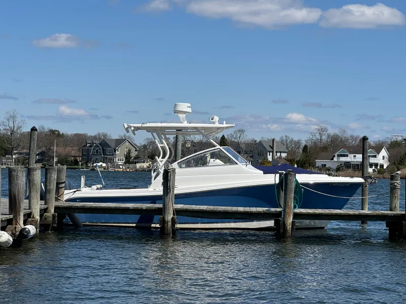 Slide: The Image of 2014 Edgewater 280 CX boat docked by waterfront homes under a clear blue sky. - 2