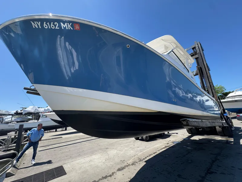 Slide: The Image of 2014 Edgewater 280 CX boat on forklift, blue hull, sunny day at marina. - 5