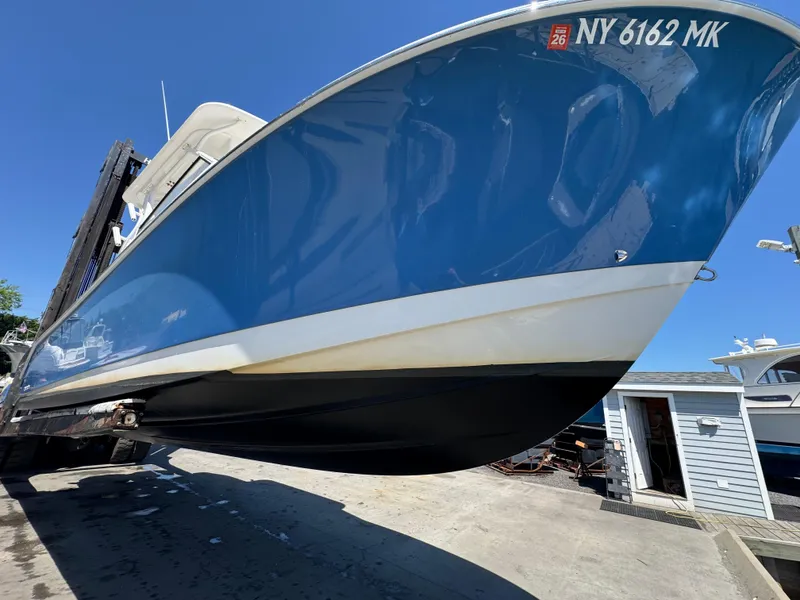 Slide: The Image of 2014 Edgewater 280 CX boat on a lift, blue hull, clear sky background. - 6