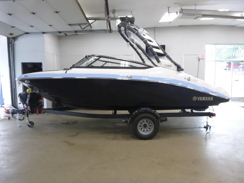 The Image of 2025 Yamaha Boats 195S in showroom, sleek black and white design on trailer. - 1