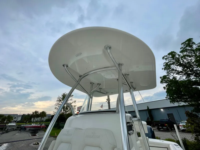 Slide: The Image of 2019 Regulator 23 boat with T-top, parked outdoors under cloudy sky. - 13
