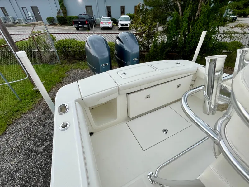 Slide: The Image of 2019 Regulator 23 boat with dual 150 engines, parked near a fence and greenery. - 8