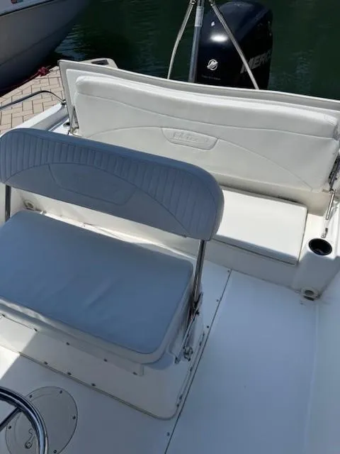 Slide: The Image of 2012 Boston Whaler 180 Dauntless boat interior with cushioned seating and Mercury outboard motor. - 13